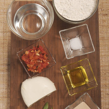 1 ¾ de taza de harina (225 gramos) ½ cucharita de sal 11 gramos de levadura seca 2 cucharadas de aceite de oliva 2/3 de taza de agua Ingredientes para aderezar: ¼ de taza de salsa italiana de jitomate 150 gramos de queso Mozzarela 12 hojas de albahaca Aceite de oliva al gusto