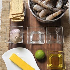 2 cabezas de ajo 1 cucharada de vinagre ¼ de taza de aceite de oliva 3 pimientas negras 90 gramos de mantequilla 1 kilo de camarones Sal al gusto Galletas saladas Limón