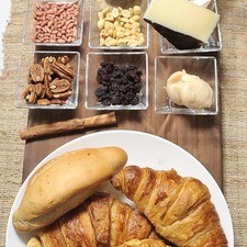 6 panes duros 2 cucharadas de manteca de puerco 200 gramos de piloncillo 1 ½ tazas de agua 1 raja de canela ½ barra de mantequilla 100 gramos de queso ¼ de taza de nuez ¼ taza de cacahuates ¼ taza de piñones ¼ taza de uvas pasa