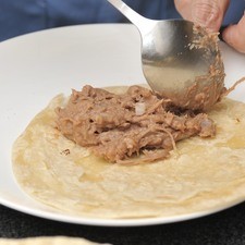 Poner esta mezcla de manera generosa casi en el extremo de una tortilla de harina.