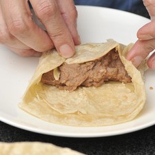 Agregar un puñito de queso a lo largo del relleno, recoger los extremos para evitar que se salga el relleno y enrollar.