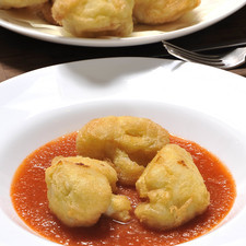 Servir la salsa caliente en un plato hondo y colocar los trozos de coliflor capeada adentro.