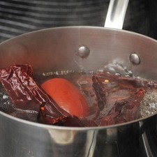 Abrir los chiles con una tijera, quitarles el rabo, las semillas y las venas. Colocar en una olla honda junta con el jitomate y agregar agua suficiente para cubrirlos. Hervir durante 5 minutos, apagar el fuego y dejar reposar 5 minutos más.