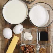 2 tazas de leche 1 barra de mantequilla (90 gramos) 2 huevos 1 ½ taza de azúcar 2 cucharadas de vainilla 1 cucharada de polvo de hornear 1 cucharada de harina ½ cucharadita de canela en polvo 1 pizca de nuez moscada 3 tazas de pan bolillo en trozos ½ taza de nueces ½ taza de pasas