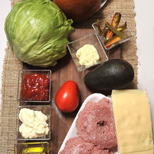 600 gramos de carne molida de res 2 cucharadas de mostaza Dijón ½ cucharadita de sal Aceite de oliva al gusto 4 panes para hamburguesa 1 lechuga 1 jitomate Rajas de chile jalapeño 1 aguacate Mayonesa al gusto Salsa catsup al gusto 4 rebanadas de queso gruyere
