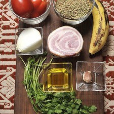 ¼ de kilo de lentejas 2 jitomates 1 trozo de cebolla 1 diente de ajo 100 gramos de tocino o panceta 1 cucharada de aceite de oliva 1 plátano macho 10 hojas de cilantro Sal al gusto