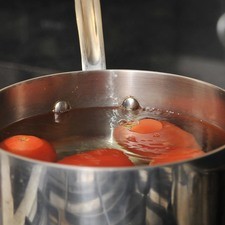 Hacer una incisión en forma de cruz en la base de los jitomates para cortar solamente la piel. Poner suficiente agua a hervir a fuego alto en una olla honda y grande, agregar los jitomates, cocer 30 segundos.