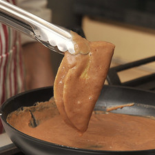Para armar las enfrijoladas, pasar las tortillas ya sofritas por la mezcla caliente de frijoles con ayuda de la pinza.