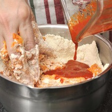Colocar la harina de maíz en un tazón y agregarle poco a poco los chiles molidos, sólo lo suficiente para formar una masa roja suave pero firme, que no sea pegajosa.