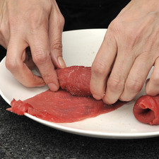 Salpimentar los filetes de res por ambos lados. Agregar un poco de verduras cocidas. Enrollar y fijar con palillos de madera.