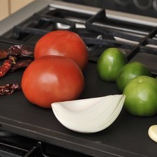 Tostar los chiles, los tomates, el ajo y la cebolla sobre el comal. Darles vuelta con unas pinzas varias veces para que se cuezan parejo.