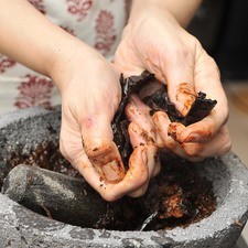 Moler en el molcajete el ajo y chiles.