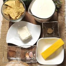 1 manojo de espinacas 90 gramos de mantequilla 2 dientes de ajo ½ cucharita pimienta blanca ½ cucharadita nuez moscada 3 tazas de crema de leche de vaca 1 taza de queso parmesano rallado Sal al gusto 95 gramos de queso crema 1 pan campesino 1 bote de corazones de alcachofa 100 gramos queso mozzarella Totopos