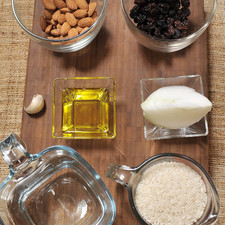 1 taza de arroz ¼ de cebolla 1 diente de ajo Aceite de oliva, al gusto 2 tazas de agua Sal, al gusto ½ taza de almendras ½ taza de pasas