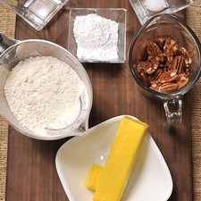 Ingredientes: 3/4 taza de nuez 1 1/2 tazas de harina de trigo 1/4 cucharita de sal 1 cucharada de agua 4 cucharadas de azúcar glass (pulverizada) 100 gramos de mantequilla con sal