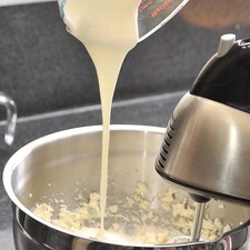 Añadir la crema poco a poco sin dejar de batir. Parar y bajar la mezcla de los lados, continuar batiendo hasta que la mezcla esté bien integrada.