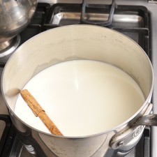 Disolver la maicena en la media taza de agua. Colocar la leche con la canela en una sartén honda y calentar hasta que suelte el hervor.