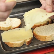 Colocar una rebanada de queos gruyere sobre cada rebanada y hornear hasta que el queso se derrita.