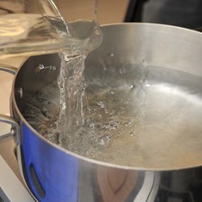 Poner a calentar una cebolla partida por la mitad y una cabeza de ajo en dos litros de agua.
