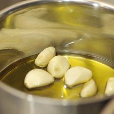 Poner a calentar a lumbre muy bajita el aceite de oliva junto con el ajo ya pelado hasta que se suavice.