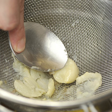 Colar el ajo y aplastar a través del colador para que se forme un puré. Depositar el puré dentro del aceite.