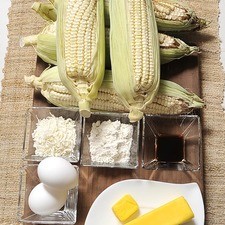 6 elotes 1 barra de mantequilla (90 gramos) 2 huevos 1 lata de leche condensada 1 cucharada de vainilla 1/3 taza de coco rallado Harina para engrasar el molde Mantequilla para engrasar el molde S 520 1475637729