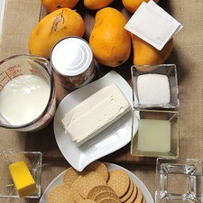 1/4 taza de agua 190 gramos de queso crema 1 taza de yogur natural 3 cucharadas de jugo de limón 1 lata de leche condensada 6 piezas de mango 14 gramos de grenetina natural 3 cucharadas de azúcar blanca 5 cucharadas de mantequilla 340 gramos de galletas marías