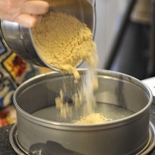 Combinar la galleta molida con el azúcar y la mantequilla en un tazón, vaciar dentro del molde de pastel y presionar hacia el fondo del mismo hasta comprimir bien. Hornear durante 10 a 15 minutos hasta que se dore la galleta. Dejar enfriar.