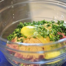 Mientras se cuece un poco la salsa, preparar las albóndigas mezclando con las manos en un tazón la carne molida con el pan molido, un diente de ajo picado, las ramitas de cilantro picado, los huevo.