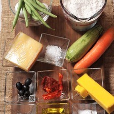2 cucharadas de polvo para hornear (levadura química) 2 tazas de harina de trigo 100 gramos de mantequilla 4 cucharadas de aceite de oliva 1 pizca de nuez moscada 2 piezas de huevo 2 piezas de yema de huevo sal de grano al gusto 10 piezas de ejotes 1 pieza de zanahoria 1 pieza de calabacita 3 piezas de jitomate deshidratado 150 gramos de queso comté 5 piezas de aceitunas negras sin hueso pimienta al gusto sal al gusto