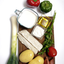 2 lomos de bacalao sin espinas 2 papas 2 tazas de leche entera 1 pimiento verde 1 pimiento rojo 1 poro 3 dientes de echalote 1 jitomate Harina de trigo al gusto Aceite de oliva virgen extra al gusto Sal al gusto Pimienta al gusto Perejil picado al gusto