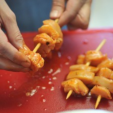 Ensartar los cubos de pollo en las brochetas.