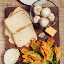 1 taza de champiñones ¼ cebolla 1 diente de ajo 6 huevos 6 rebanadas de jamón 12 flores de calabaza Sal al gusto Pimienta al gusto Pan de caja Mantequilla Aceite de oliva al gusto