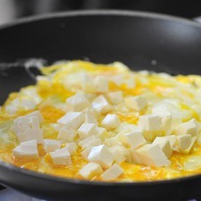 Cuando todavía está tierno el huevo, agregar el queso cortado en dados, cocer 1 minuto más.