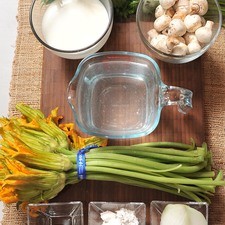1 manojo de flor de calabaza 1 diente de ajo 1/4 pieza de cebolla blanca 2 cucharadas de harina de trigo 1 taza de leche de vaca 1 taza de champiñones sal al gusto pimienta negra molida al gusto 2 tazas de caldo de pollo 1/4 manojo de perejil fresco