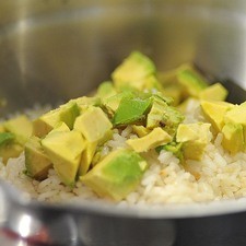 Agregar el arroz cocido, el aguacate picado en cubos, el cuarto de cebolla finamente picada, el cilantro picado.