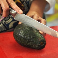 Para preparar el guacamole, cortar el aguacate a la mitad, retirar la semilla con un cuchillo.