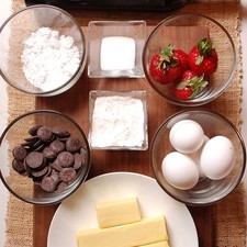 200 gramos de chocolate amargo para repostería 225 gramos de mantequilla sin sal 2 piezas de yema de huevo 2 piezas de huevo 2 cucharadas de azúcar blanca 3 cucharadas de harina de trigo 4 piezas de fresa azúcar glass (pulverizada) al gusto 1 botella de vino tinto norte 32 etiqueta negra