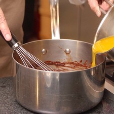 Derretir el chocolate en una olla honda con un poco de agua a lumbre muy bajita. Mover constantemente con el batidor de huevos. Cuando el chocolate esté completamente derretido, retirar la olla de la lumbre y agregar la mantequilla derretida poco a poco. Mover con el globo para que se integre.