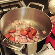 Cocer las alubias en agua con un poco de sal hasta que estén blandas, si se remojan la noche anterior se cuecen en 2 horas y media o tres. Cortar el tocino y el jamón en cuadros, el chorizo y las salchichas en rodajas de 2 centímetros, la cebolla en filetes tipo juliana. En una olla honda grande a fuego alto freír el tocino 2 o 3 minutos hasta que esté cocido, pero no dorado. Agregar el chorizo, la salchicha, el jamón, el ajo y la cebolla. Freír por 3 a 5 minutos revolviendo los ingredientes.
