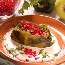 Rellenar los chiles con la mezcla de carne y fruta, puede estar tibia o caliente. Servir bañados con la nogada fría. Espolvorear con el resto del perejil picado y los granos de granada.