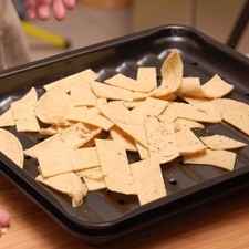 Para preparar los chilaquiles, cortar las tortillas en tiras delgadas. Poner al horno a 300°F (150°C) durante 20 ó 30 minutos, volteando de vez en cuando con la pala hasta que estén doradas pero no quemadas.