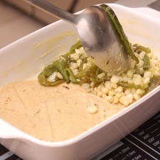 Colocar una capa de tortillas, otra de elotes y chile.