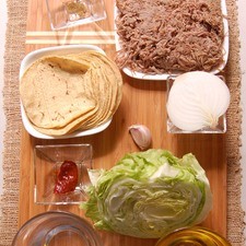 300 gramos de carne deshebrada de res 4 piezas de jitomate guaje 12 piezas de tortilla de maíz 1/2 pieza de cebolla blanca 1/2 pieza de lechuga 1 taza de agua sal al gusto 1 pizca de comino molido aceite de canola al gusto 1 pieza de chile chipotle adobado 1 diente de ajo
