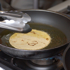 Pasar las tortillas, una por una, por un sartén con aceite caliente utilizando una pinza. Escurrir el exceso de aceite y reservar.