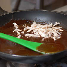 En otra sartén, calentar el mole, agregar el pollo desmenuzado y rectificar sazón. Dejar hervir un poco. Si se espesa demasiado, agregar agua al gusto o caldo de pollo. Una vez listo el mole, mover el pollo hacia un lado del sartén.