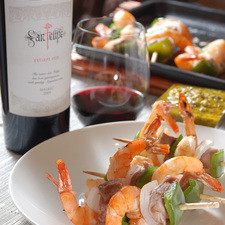 Servir las brochetas bañadas con la salsa y maridadas con una copa de vino tinto San Felipe Estirpe.