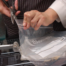 Para preparar la máquina de tortillas, cortar una bolsa de plástico en dos partes y colocarlas dentro de la máquina. Si no se tiene máquina, se puede aplastar entre dos libros pesados. Poner a calentar el comal a lumbre media.