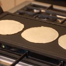 Poner la tortilla sobre el comal y proceder a hacer otra tortilla. Una vez que se tiene la segunda tortilla en la mano, colocarla sobre el comal y voltear la primera tortilla con la mano para que se cueza por el otro lado, si tienes miedo de quemarte usa una pala. Proceder a hacer la tercera tortilla. Una vez que se tiene la tercera tortilla, colocarla sobre el comal, voltear la segunda y la primera. Presionar un poco con los dedos la primera tortilla para que se infle. Proceder a hacer la cuarta tortilla.