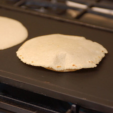 Al regresar al comal, retirar la primera tortilla y ponerla en una tortillera y proceder a poner la cuarta tortilla a cocer, voltear las otras dos tortillas, sin olvidar presionar la segunda tortilla para que se infle. Continuar con este ritmo hasta terminar de hacer las tortillas.